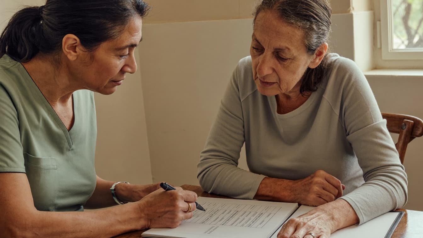 A patient and clinician reviewing a printed lab report together at a desk in a calm consultation room